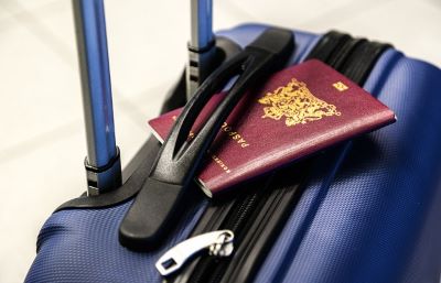 Reisepass auf blauem Koffer im Griff eingeklemmt