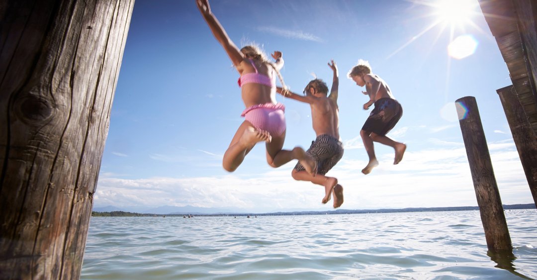 3 springende Kinder ins Wasser vom Holzsteg